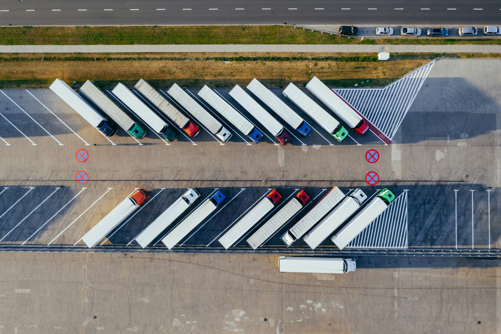 Tractor-trailers parked in angled bays across a freight yard, seen from directly overhead